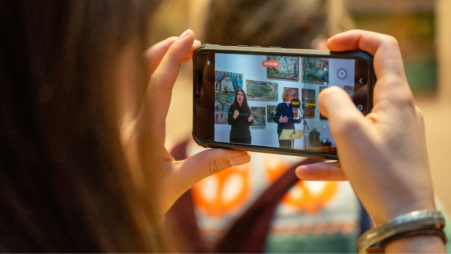 holding a mobile phone to film an event
