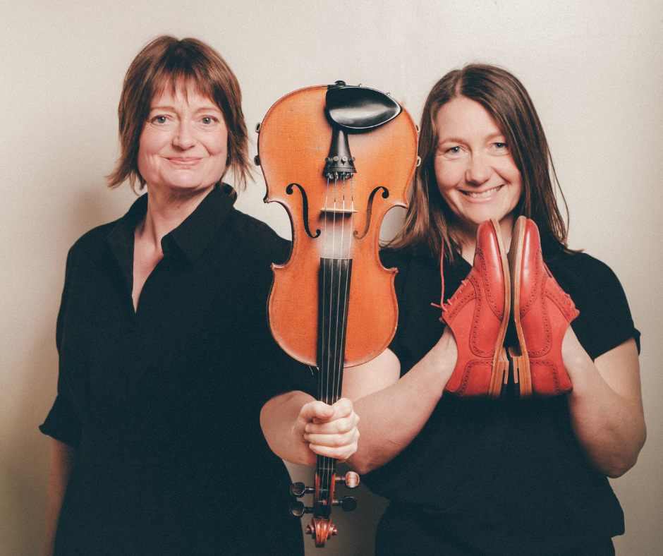 Fiddler Amy Geddes and step-dancer Alison Carlyle wearing black tops smiling at the camera; Amy holds a fiddle vertically, and Alison holds a pair of red step-dance shoes, promoting the Scottish performance Deiseil: Dancing in Time, which explores traditional stepdance and percussive music.